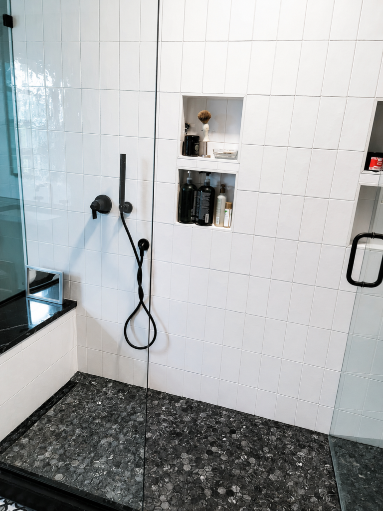White tile shower with black fixtures completed by Earth Smart Building and Remodeling